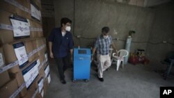 Dos trabajadores mueven un nuevo respirador artificial totalmente fabricado por empresas mexicanas.