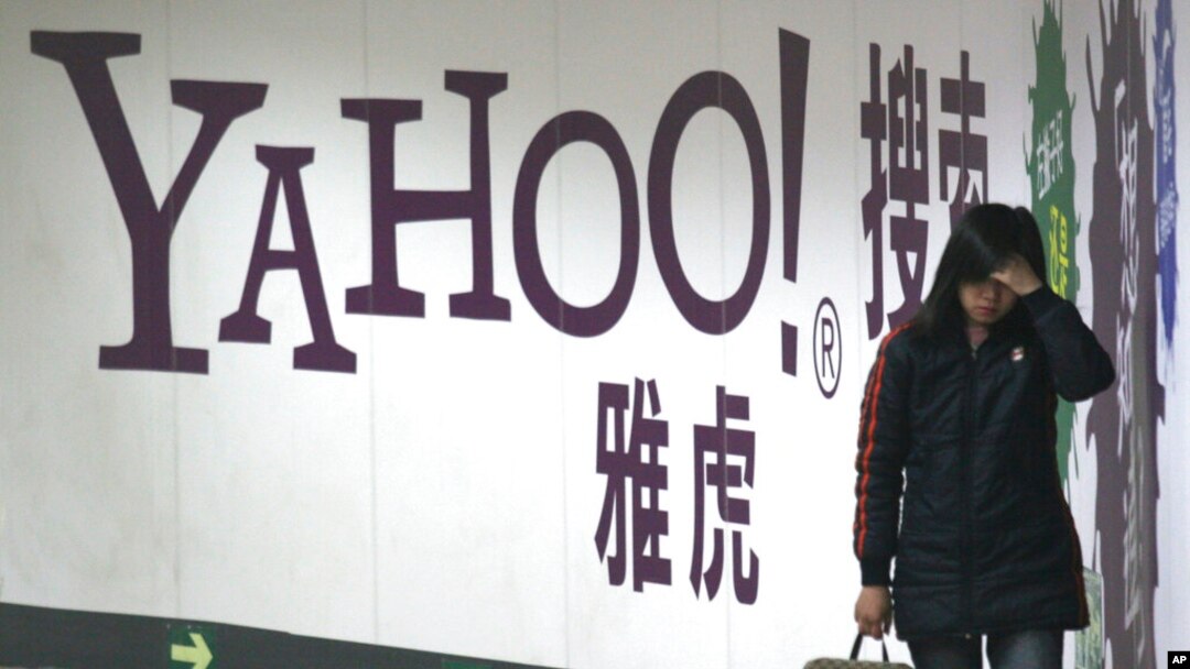 FILE - A woman walks past a Yahoo billboard in a Beijing subway station, March 17, 2006. Yahoo Inc. withdrew from the China market Nov. 1, 2021, because of an "increasingly challenging" business and legal environment.