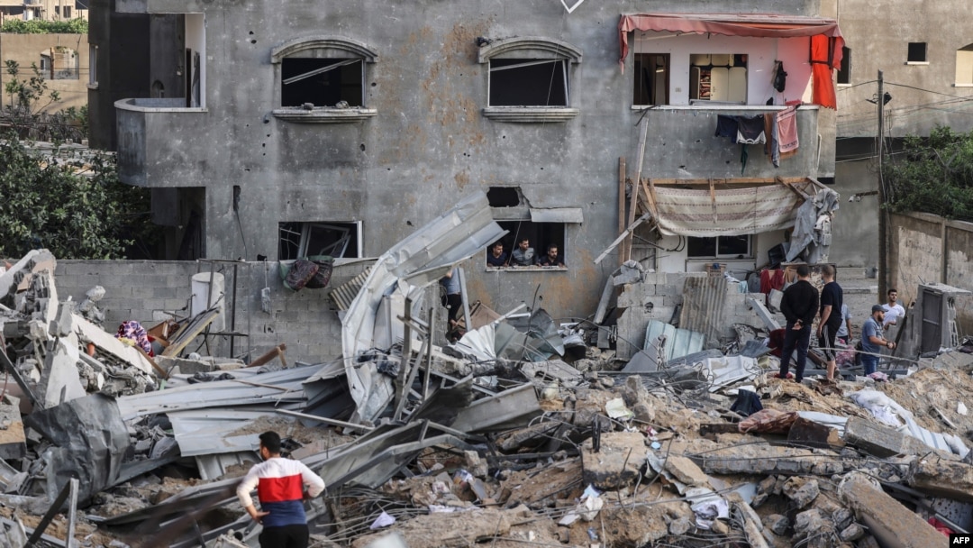 Palestinians check the damage amid the rubble of a destroyed building, following Israeli airstrikes on the northern Gaza Strip town of Beit Lahia, early May 13, 2021.
