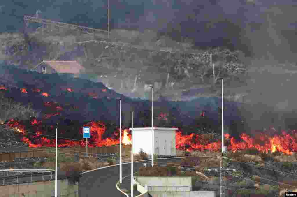 Lava rolls down behind street light posts in Los Llanos as the Cumbre Vieja volcano continues to erupt on the Canary Island of La Palma, as seen from Tajuya, Spain.
