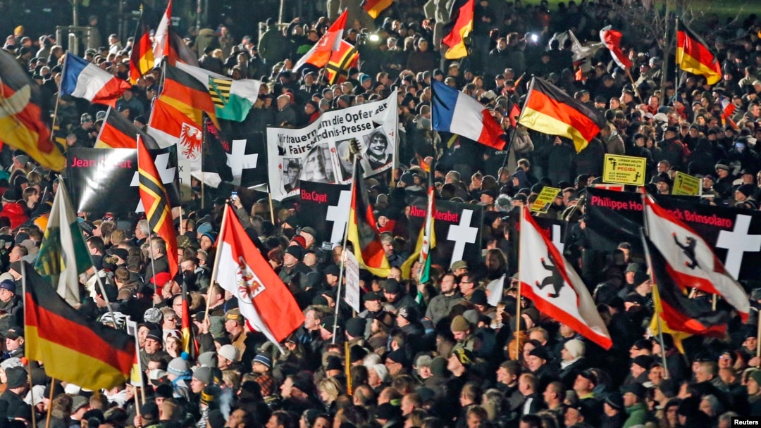 FILE - Supporters of anti-immigration movement Patriotic Europeans Against the Islamization of the West (PEGIDA) hold flags during demonstration in Dresden, Germany, Jan. 12, 2015.