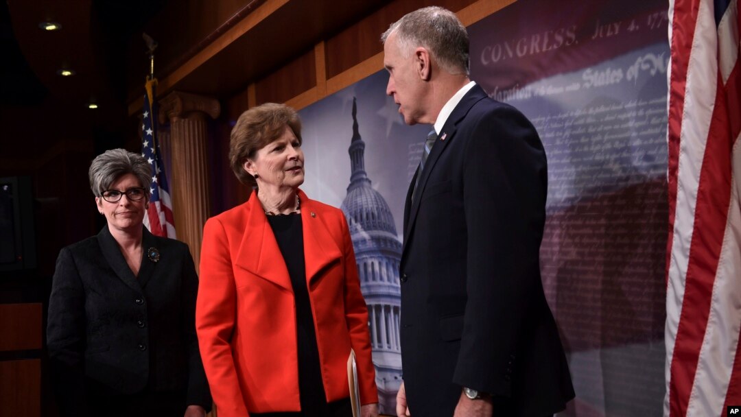 Sen. Jeanne Shaheen, D-N.H., center, and Sen. Joni Ernst, R-Iowa, left, talk with Sen. Thom Tillis, R-N.C., right, on Capitol Hill in Washington, Feb. 7, 2018,