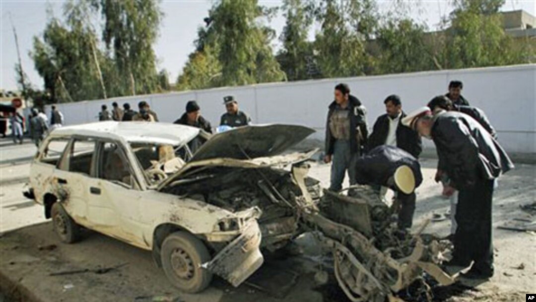 Afghan traffic officers check the engine which is all that remained of the vehicle used in a car bomb explosion, beside a damaged vehicle, after an explosion in Kandahar, south of Kabul, 11 Dec 2010