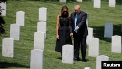 El presidente de los Estados Unidos, Donald Trump, y la primera dama, Melania Trump, se agarran de las manos entre las lápidas mientras participan en el evento anual "Flags-In" en el Cementerio Nacional de Arlington. Photo: Reuters.