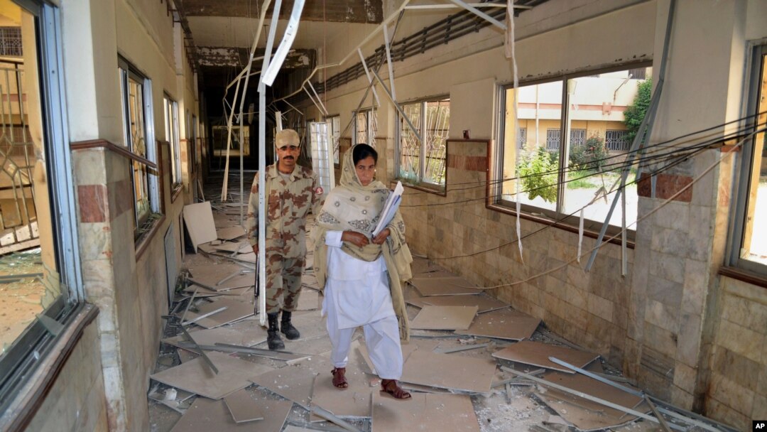 FILE - A Pakistani paramilitary soldier and a nurse walk through a corridor at the Bolan Medical complex damaged by an attack claimed by the Sunni militant group Lashkar-e-Jhangvi, in Quetta, Pakistan, June 16, 2013.