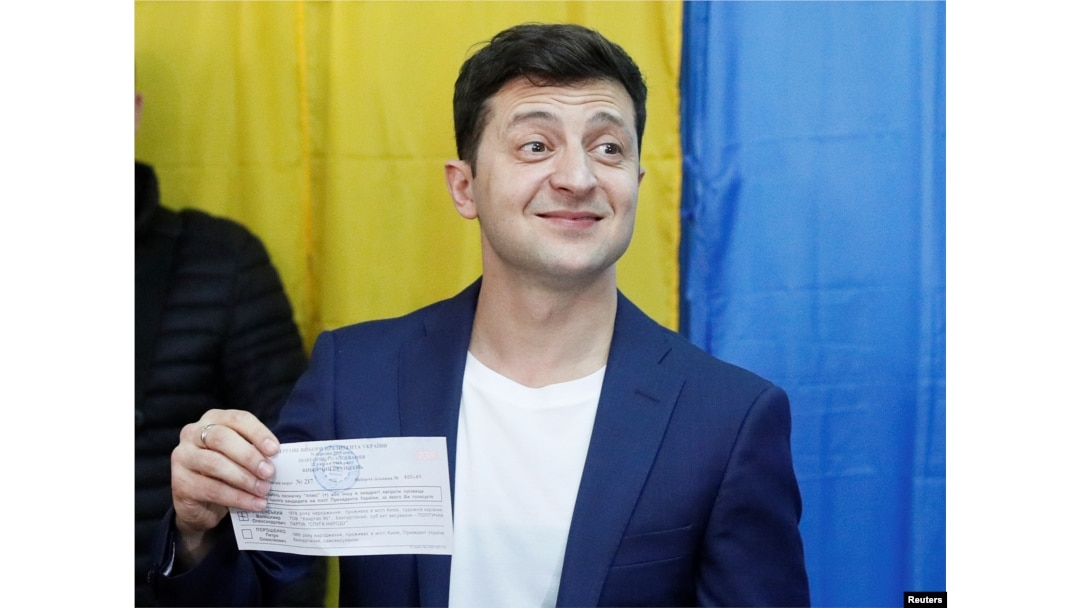 Ukrainian presidential candidate Volodymyr Zelenskiy holds up his ballot while standing in front of the media at a polling station during the second round of a presidential election in Kyiv, Ukraine, April 21, 2019.