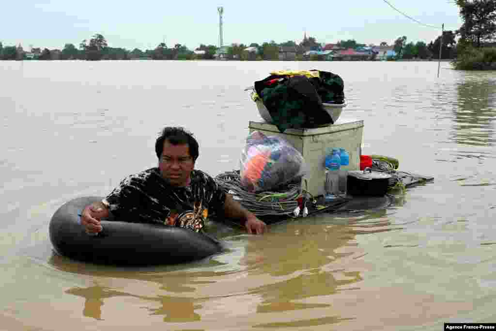 A man wades through floodwaters to transport goods on the outskirts of Phnom Penh following heavy monsoon rains.