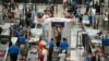 FILE - Travelers wear face coverings in the line for the south security checkpoint in the main terminal of Denver International Airport on Aug. 24, 2021, in Denver.