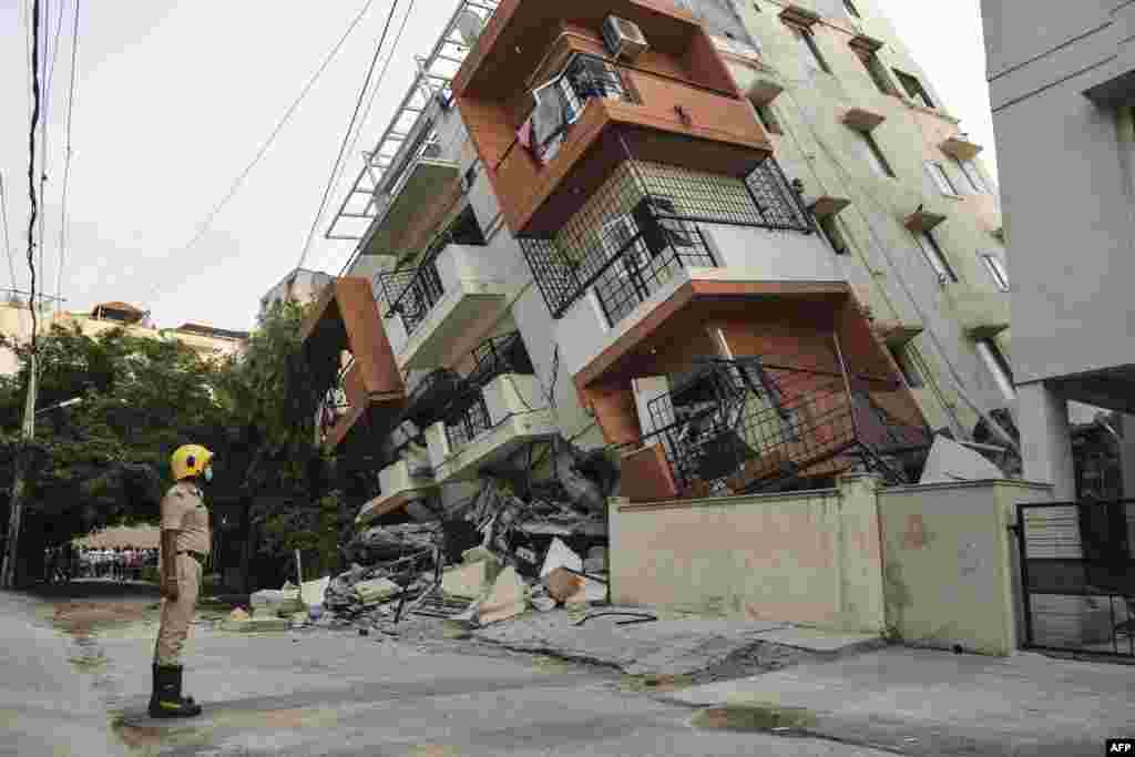 A member of the firefighting force watches as a multistory apartment building collapses, without any casualties reported, in Bangalore, India.