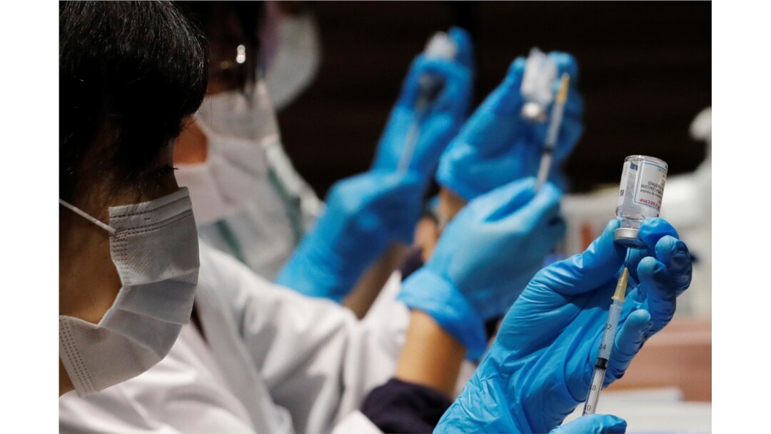 FILE - Health care workers prepare doses of the Moderna coronavirus vaccine before administering them to staffers of Japan's supermarket group Aeon at the company's shopping mall in Chiba, Japan, June 21, 2021.