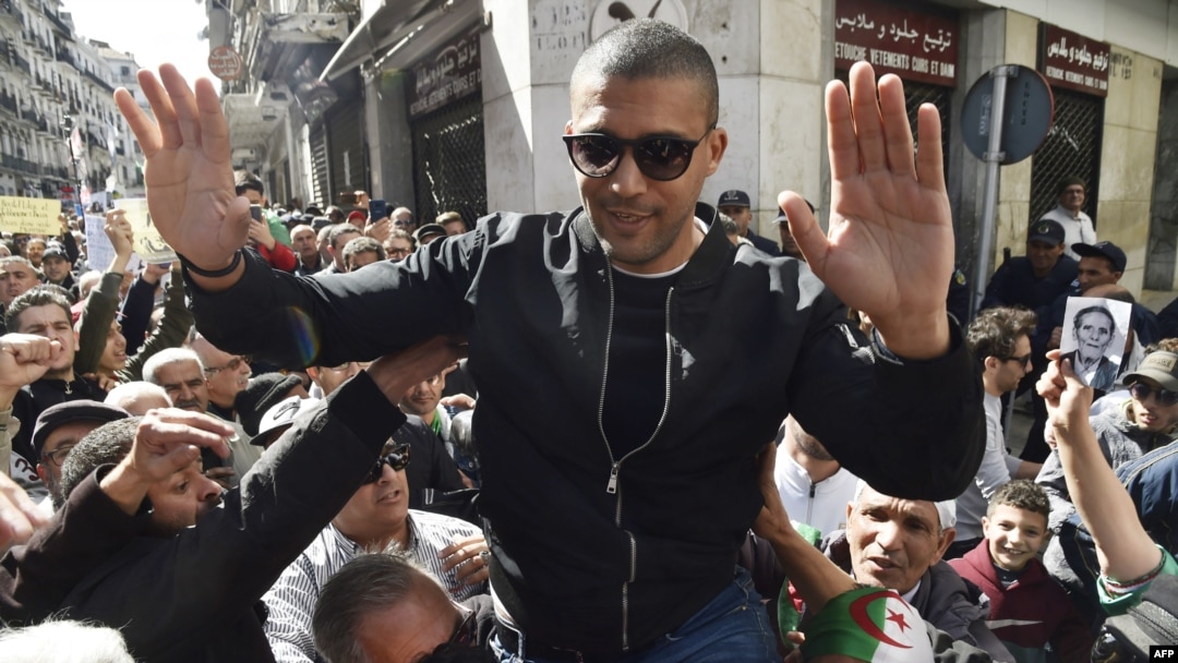 FILE - Algerian journalist Khaled Drareni is carried by protesters on their shoulders after he was briefly detained by security forces in Algiers, March 6, 2020.