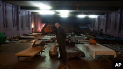 Un hombre espera ser evacuado al oeste de Ucrania, de pie junto a una cama en un teatro de la ciudad que alberga a refugiados que huyen de la ofensiva rusa en la región de Donetsk, en Pavlohrad, región de Dnipropetrovsk, Ucrania, el jueves 12 de diciembre de 2024. 