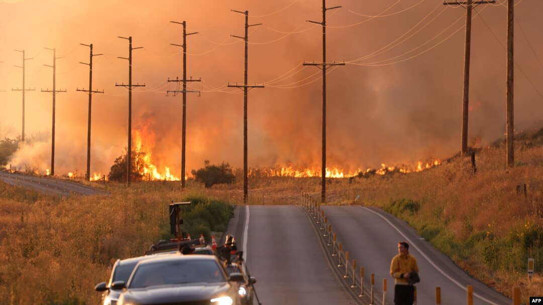 Un hombre se para en una carretera cerca de las llamas del incendio Rabbit en Moreno Valley en el condado de Riverside, California, el 14 de julio de 2023.