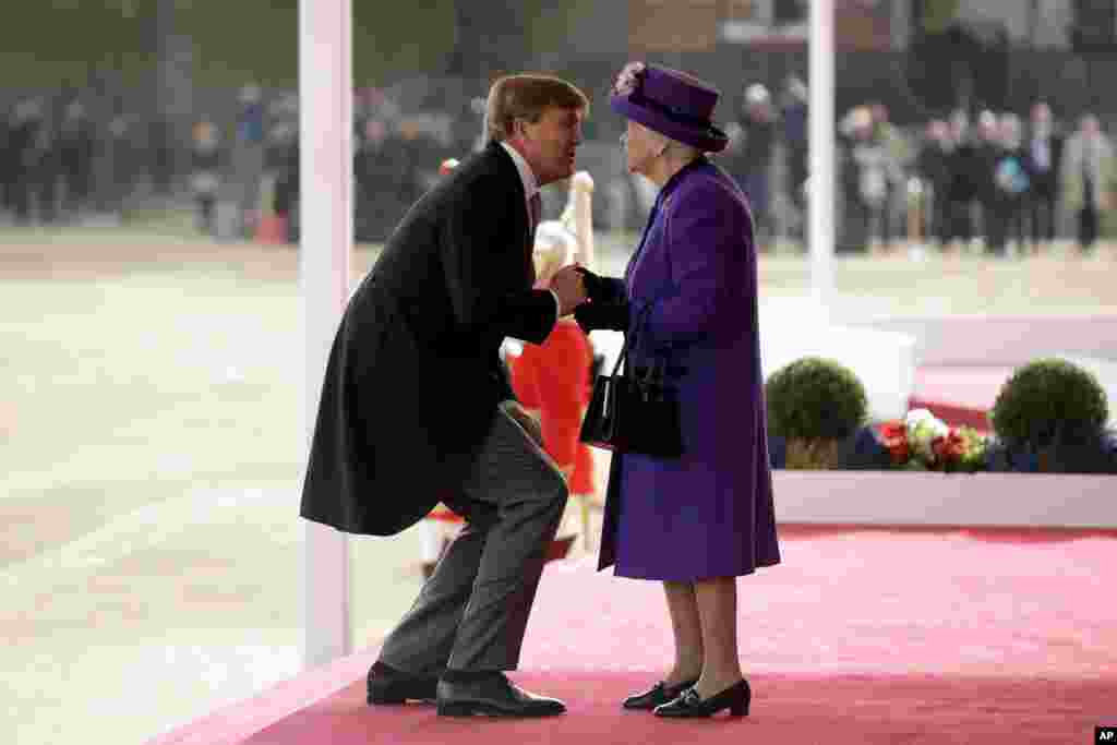 Netherlands' King Willem-Alexander bends down to kiss Britain's Queen Elizabeth II as she greets him upon his arrival during a Ceremonial Welcome on Horse Guards Parade in London, Oct. 23, 2018.