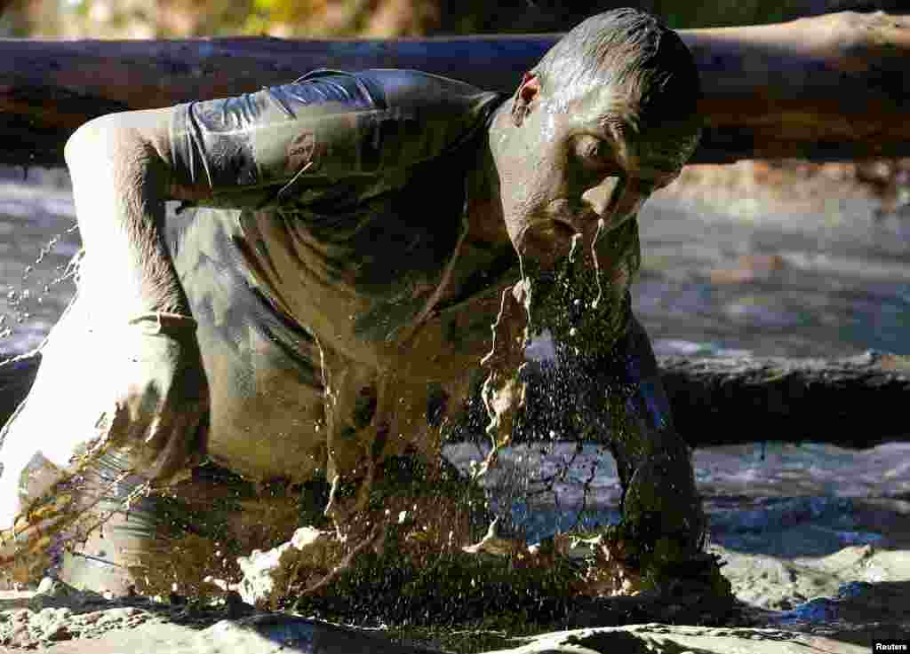 A competitor crosses a water obstacle during the Wildsau Dirt Run (Wild Boar Dirt Run) obstacle course fun race at Hellsklamm ravine in Obertriesting, Austria, Oct. 22, 2016.