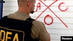 FILE - A Drug Enforcement Administration (DEA) agent marks a house after he searches it for survivors.