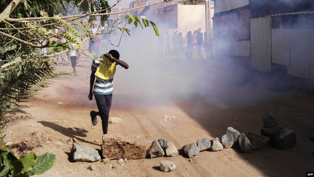 FILE - A Sudanese protester covers his face from tear gas during an anti-government demonstration in the Sudanese capital Khartoum's district of Burri, Feb. 24, 2019.