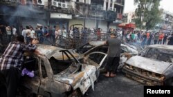 People look at cars damaged by a suicide truck attack in the Karrada shopping area of Baghdad, Iraq, July 3, 2016. 