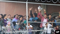 Migrantes centroamericanos esperan comida en El Paso, Texas, el miércoles 27 de marzo de 2019, en una celda de alambre erigida por la Oficina de Aduanas y Protección Fronteriza de EE.UU. para procesar una oleada de familias migrantes y menores no acompañados. 