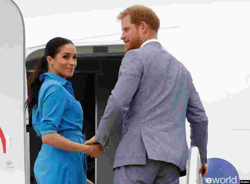 Britain&#39;s Prince Harry and Meghan, Duchess of Sussex look on before departing from Fua&#39;amotu International Airport in Tonga.