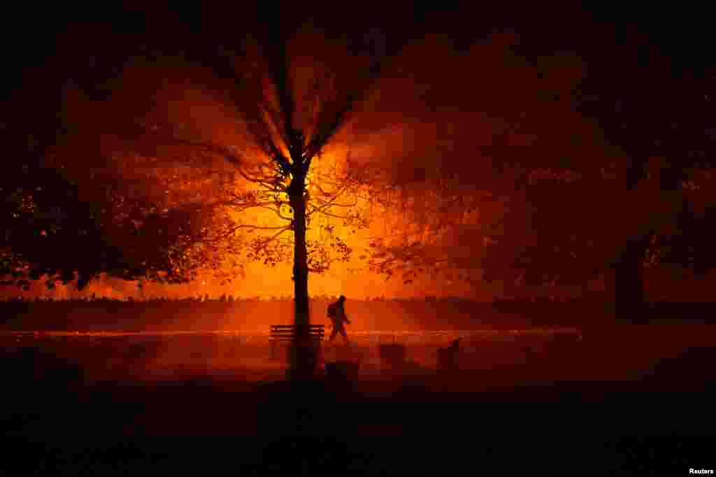 A man walks through a park during cold fog at night in Athboy, Ireland, Oct. 31, 2018.