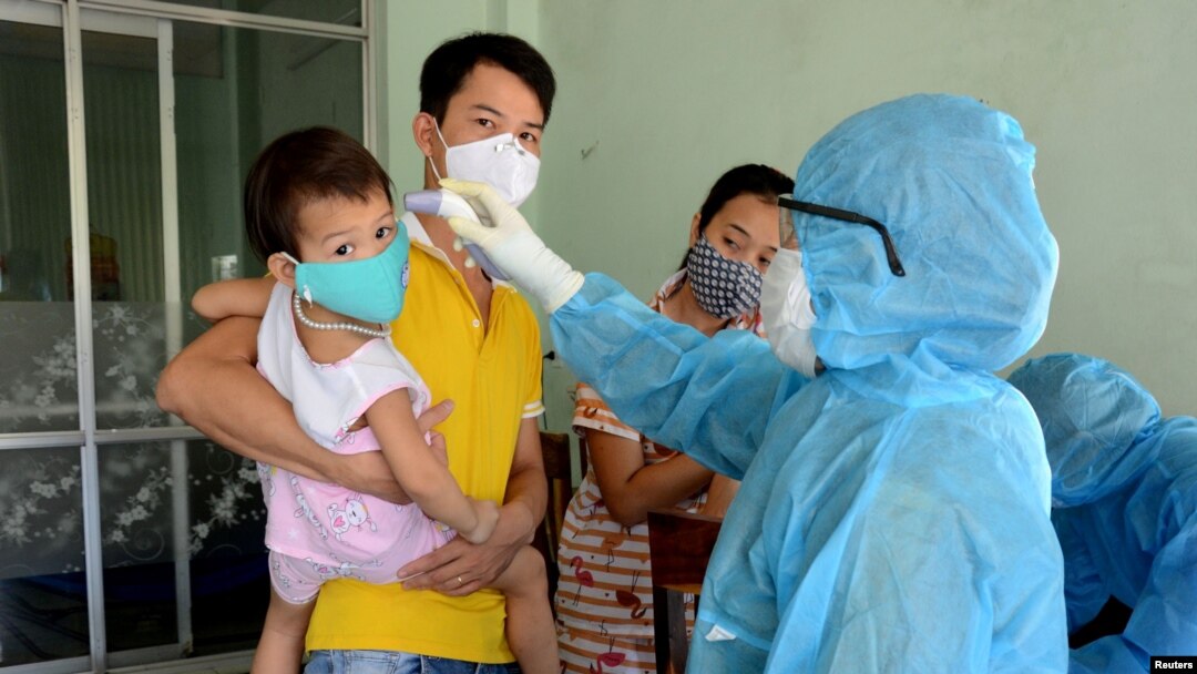 A health worker checks the temperature of residents at the area of a newly found coronavirus infected patient in Da Nang city, Vietnam, July 26, 2020.
