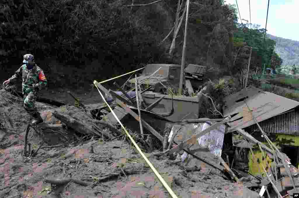 An Indonesian soldier walks past houses damaged by an earthquake-triggered landslide in Bangli, on the island of Bali, Oct. 16, 2021.