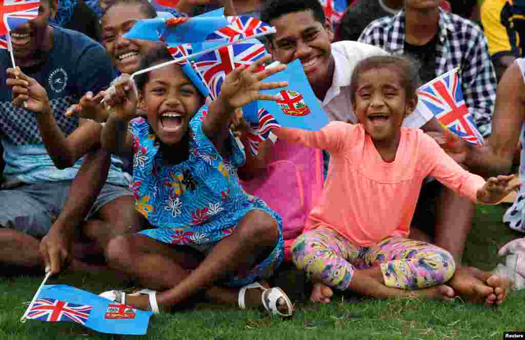 Children wave flags as Britain's Prince Harry and Meghan, Duchess of Sussex, arrive in Suva, Fiji.