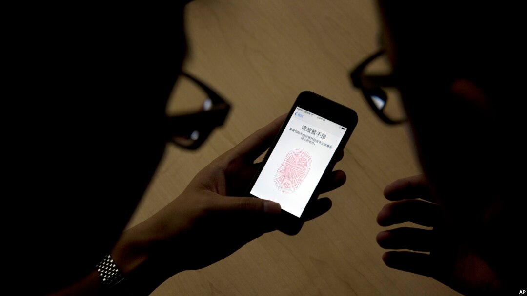 FILE - An Apple employee, right, instructs a journalist on the use of an iPhone.