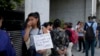 Una mujer sostiene un cartel mientras hace fila con otras personas afuera del ministerio de Capital Humano. Exigen ser atendidas por la ministra Sandra Pettovello, en Buenos Aires, Argentina, el lunes 5 de febrero de 2024.